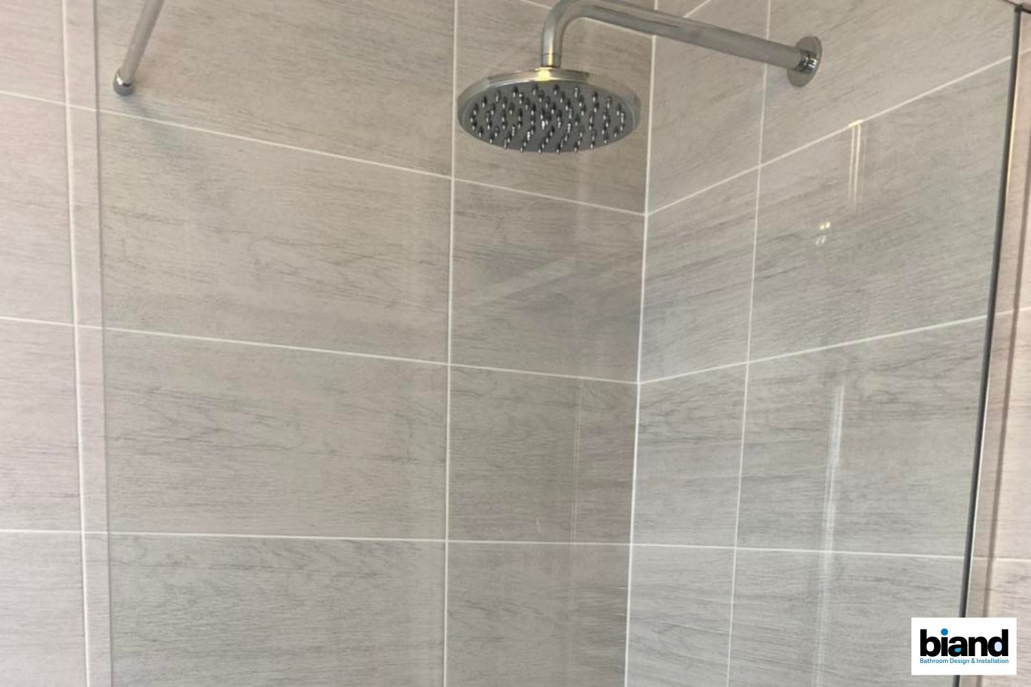 Shower with gray tiled walls and a round shower head.