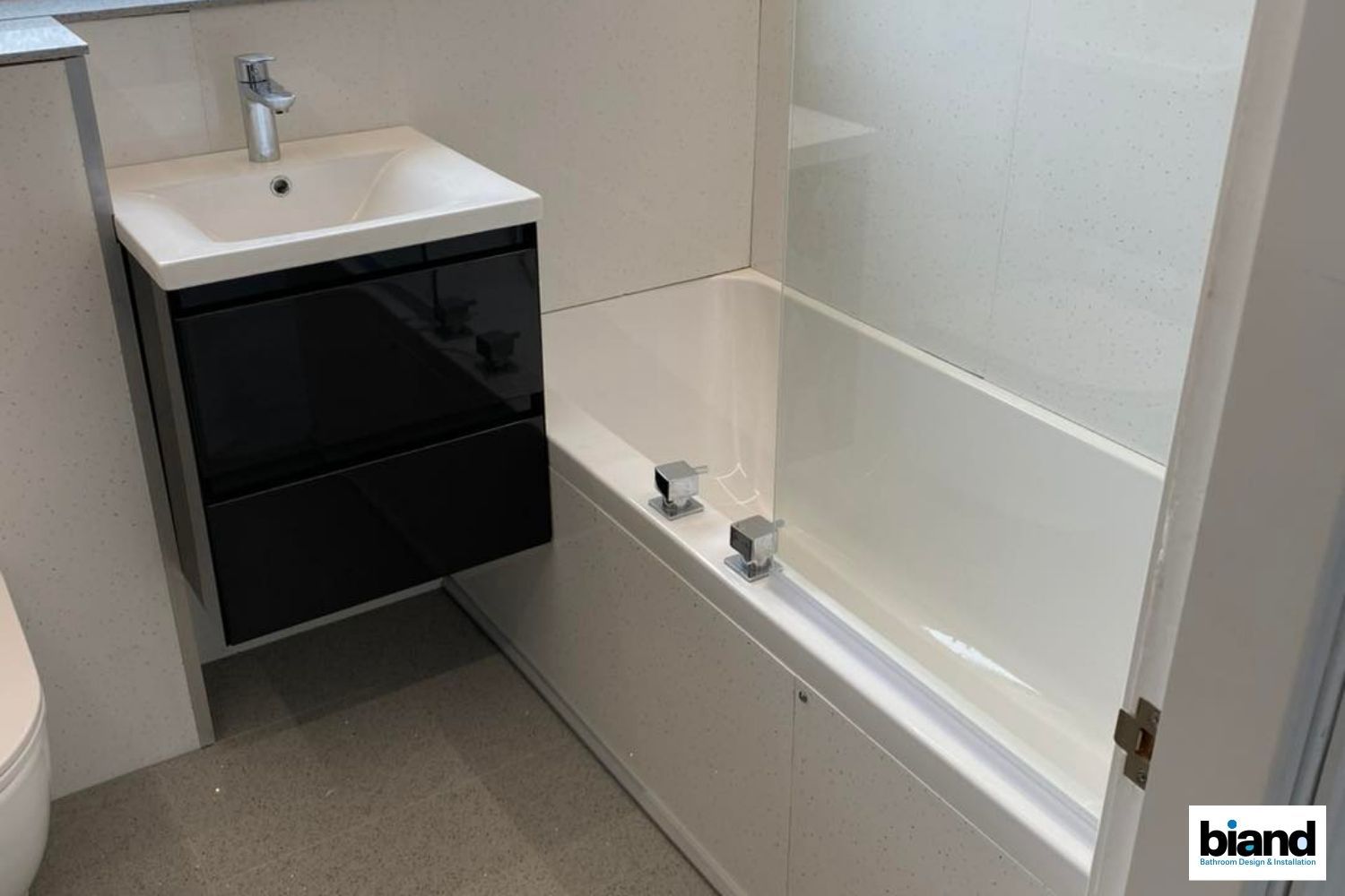 Bathroom with black vanity, white tub, and grey floor.