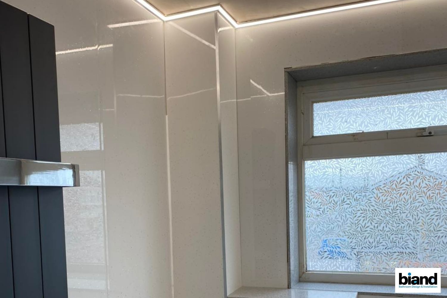 Modern bathroom with white glossy walls, window, and linear LED lights.