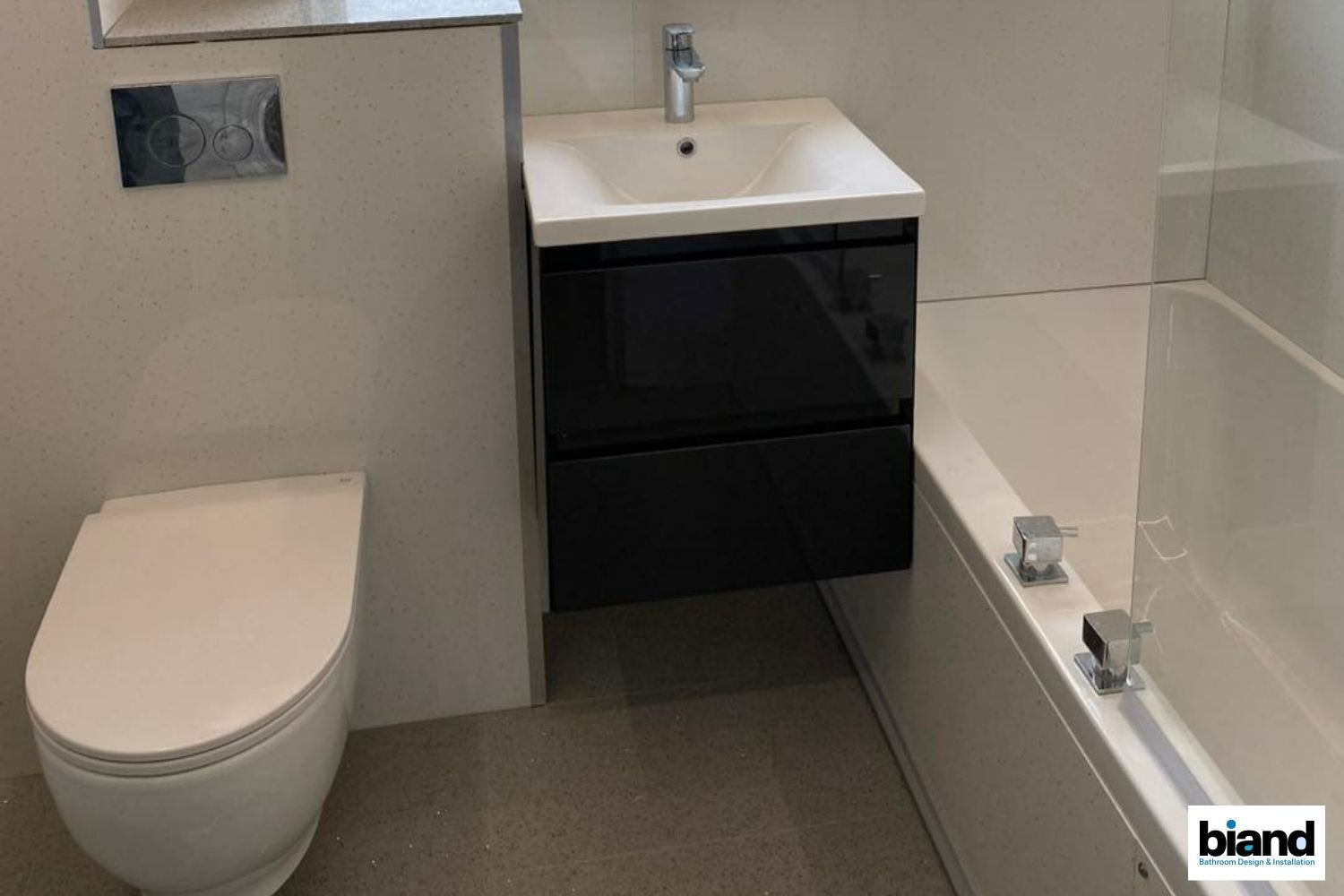 Modern bathroom with black vanity, white toilet, and bathtub.