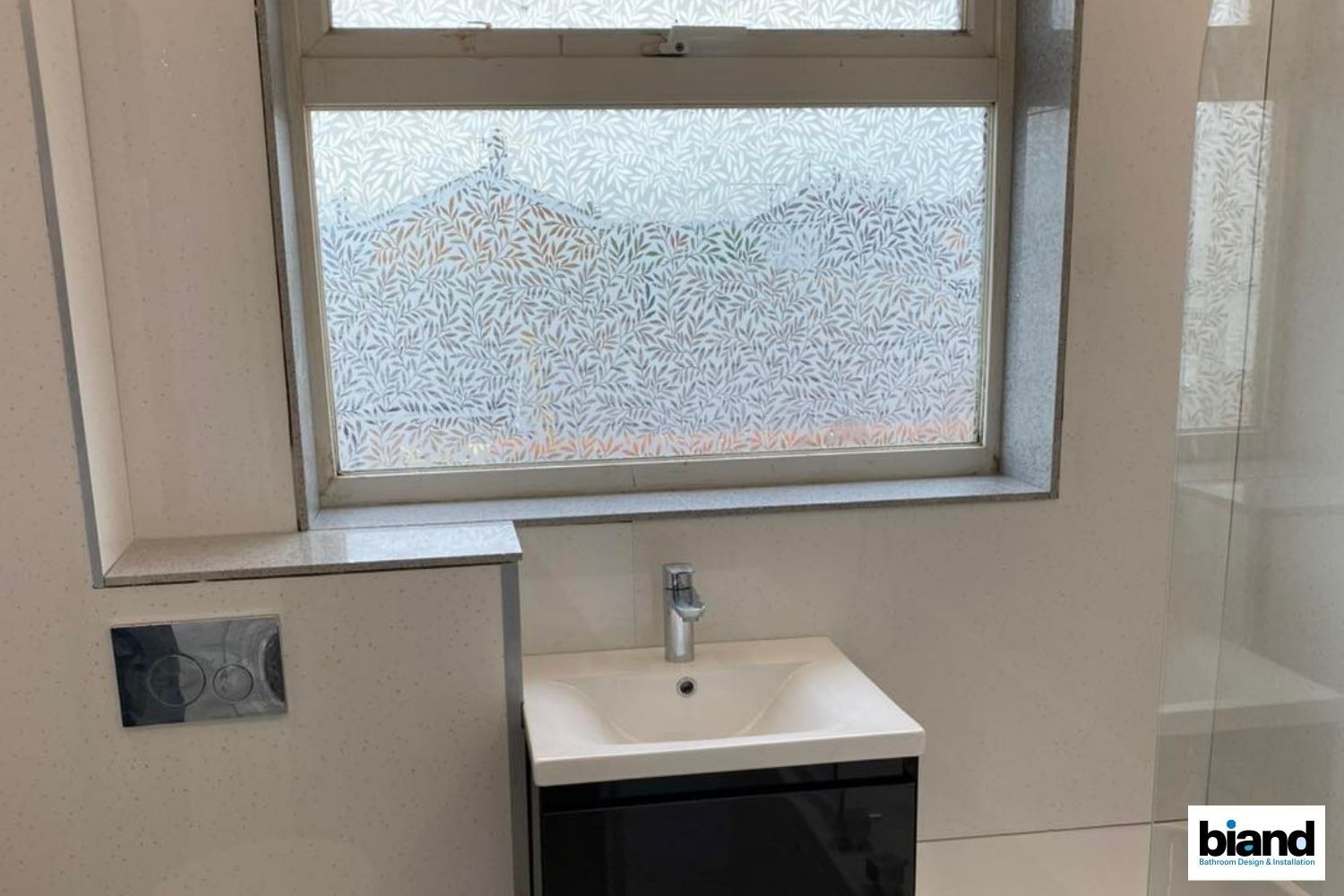 Bathroom with sink, window, and dark cabinet. Gray window frame and white walls.