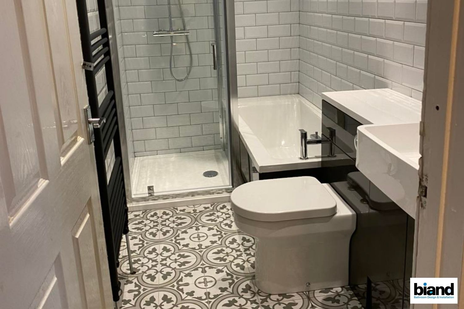 Small bathroom with patterned floor tiles, subway tile walls, shower, bathtub, and toilet.
