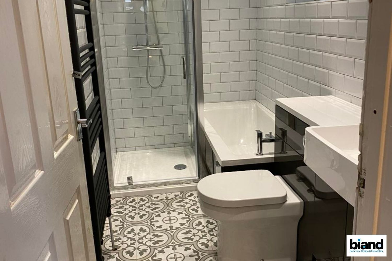 Small bathroom with patterned floor tiles, white subway tile walls, shower, tub, and toilet.