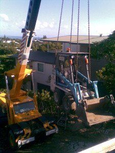 yellow crane truck lifting mini bobcat