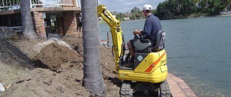 man operating yellow mini excavator