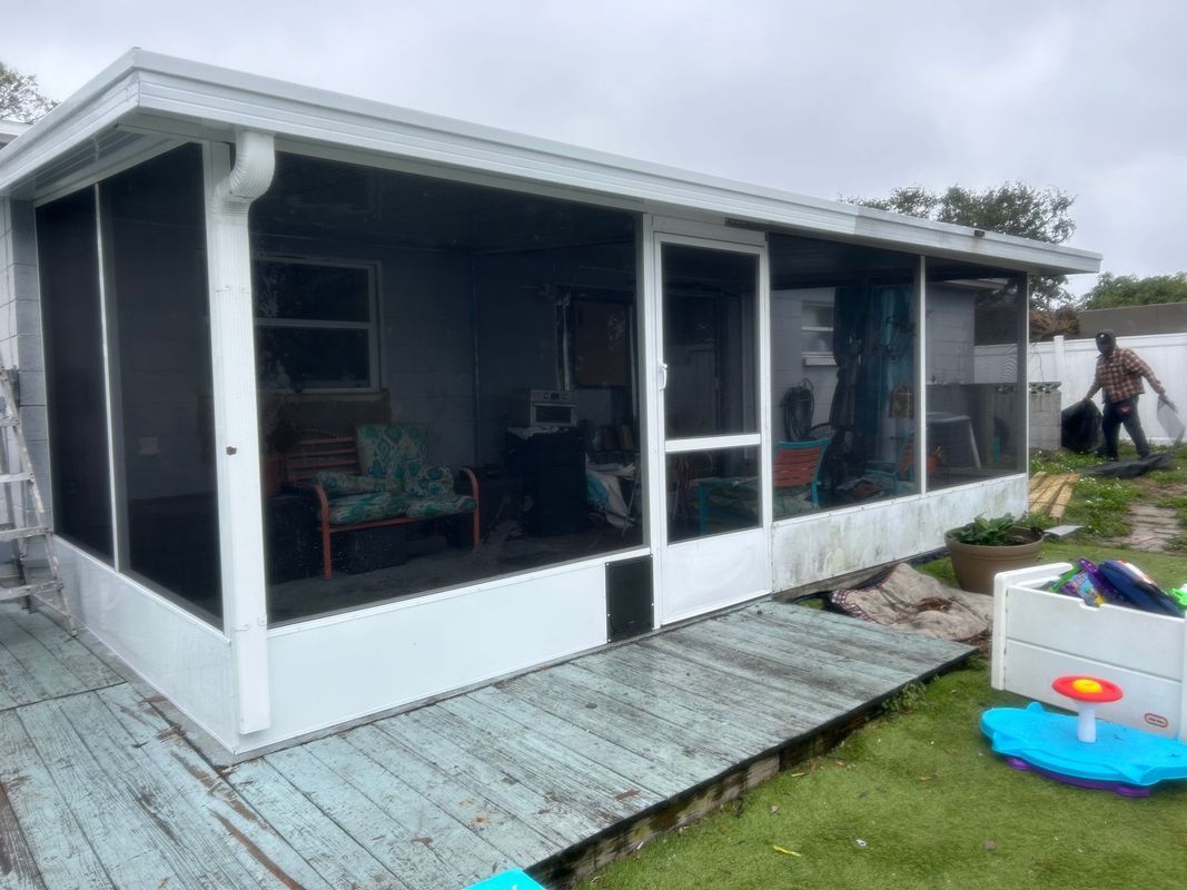A screened in porch with a dog door in the backyard of a house
