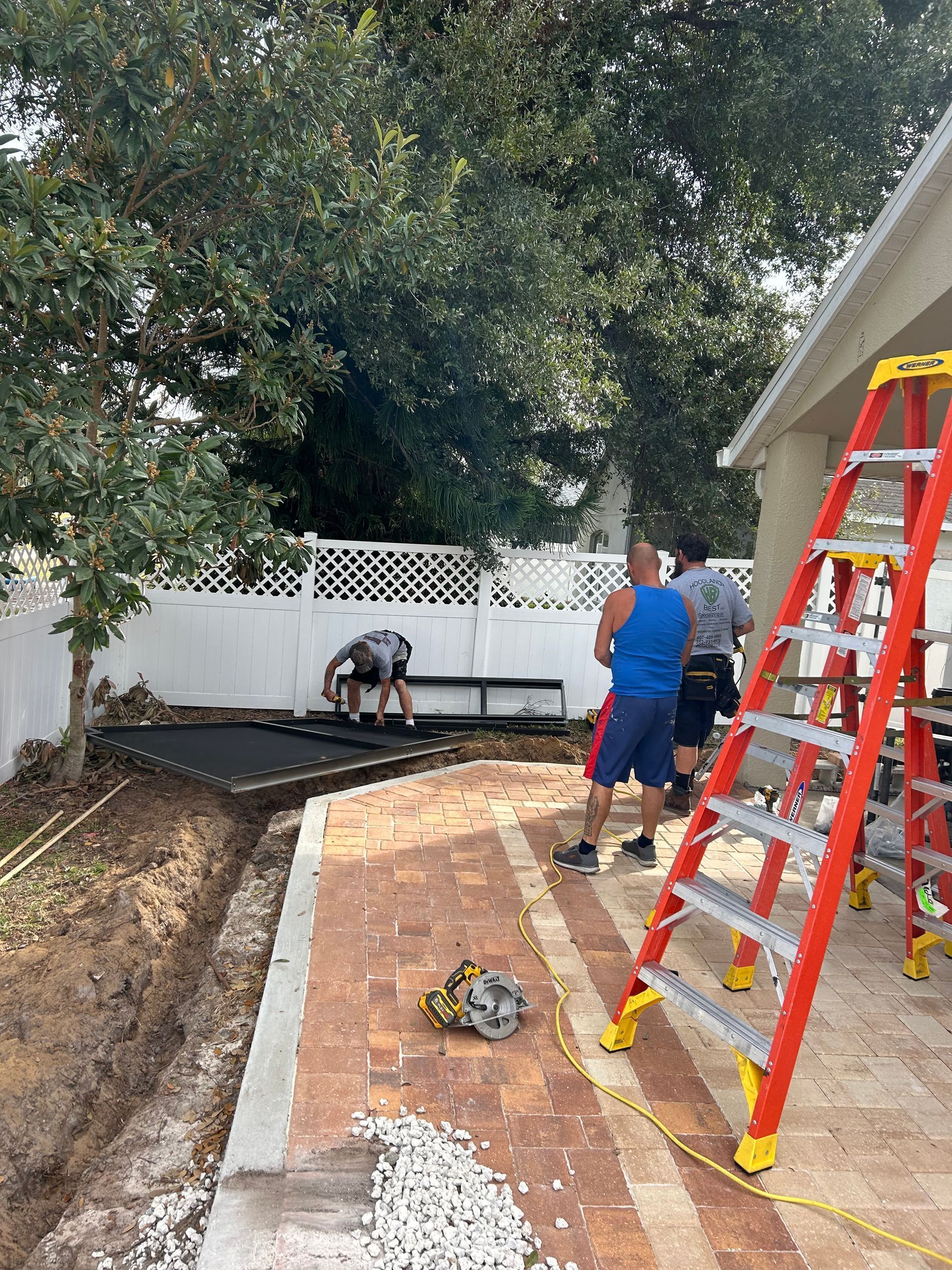 A group of men are working on a patio in a backyard