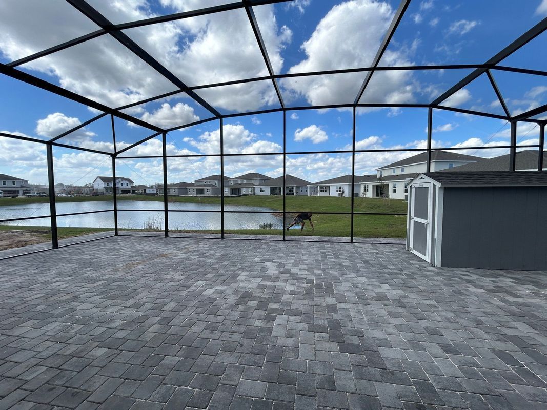 A screened in porch with a shed and a lake in the background