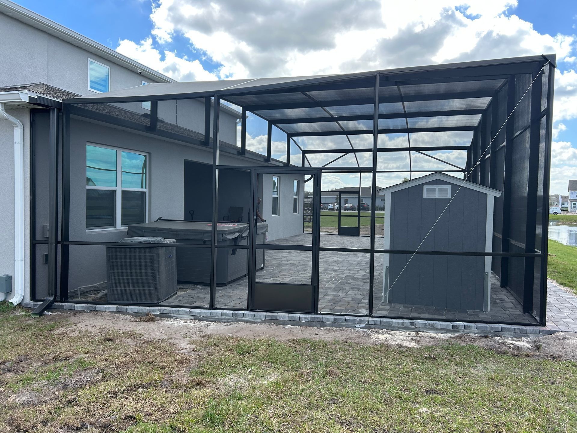 A screened in patio with a shed and a hot tub
