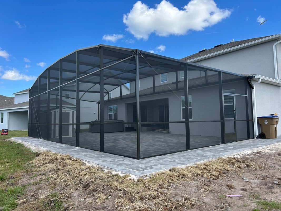 A large screened in porch in the backyard of a house