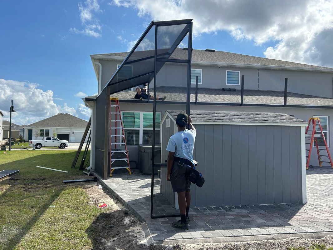 A man is standing in front of a house looking at a screened in porch