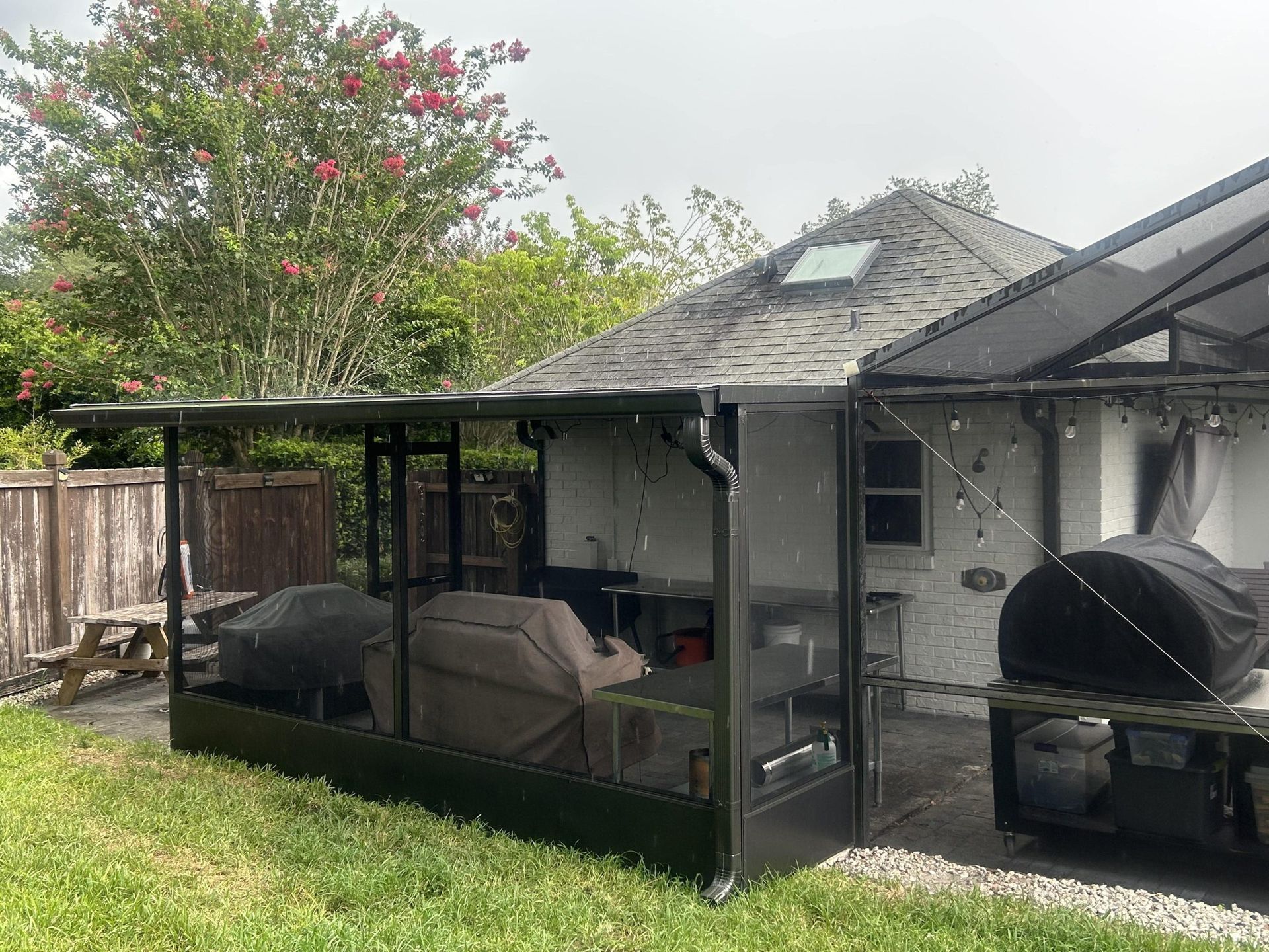 A house with a screened in porch and a grill in the backyard