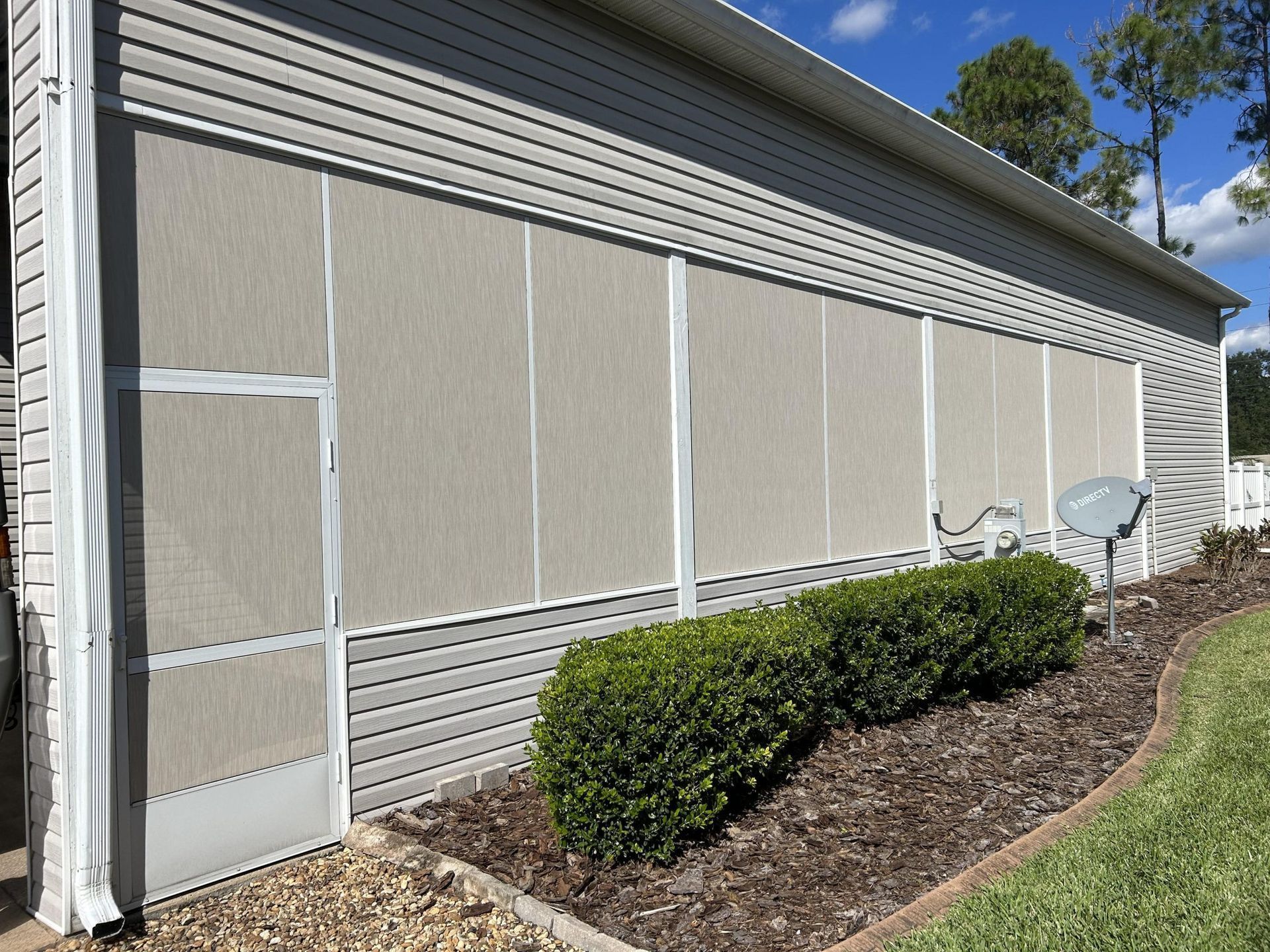 A house with a screened in porch and a satellite dish on the side of it
