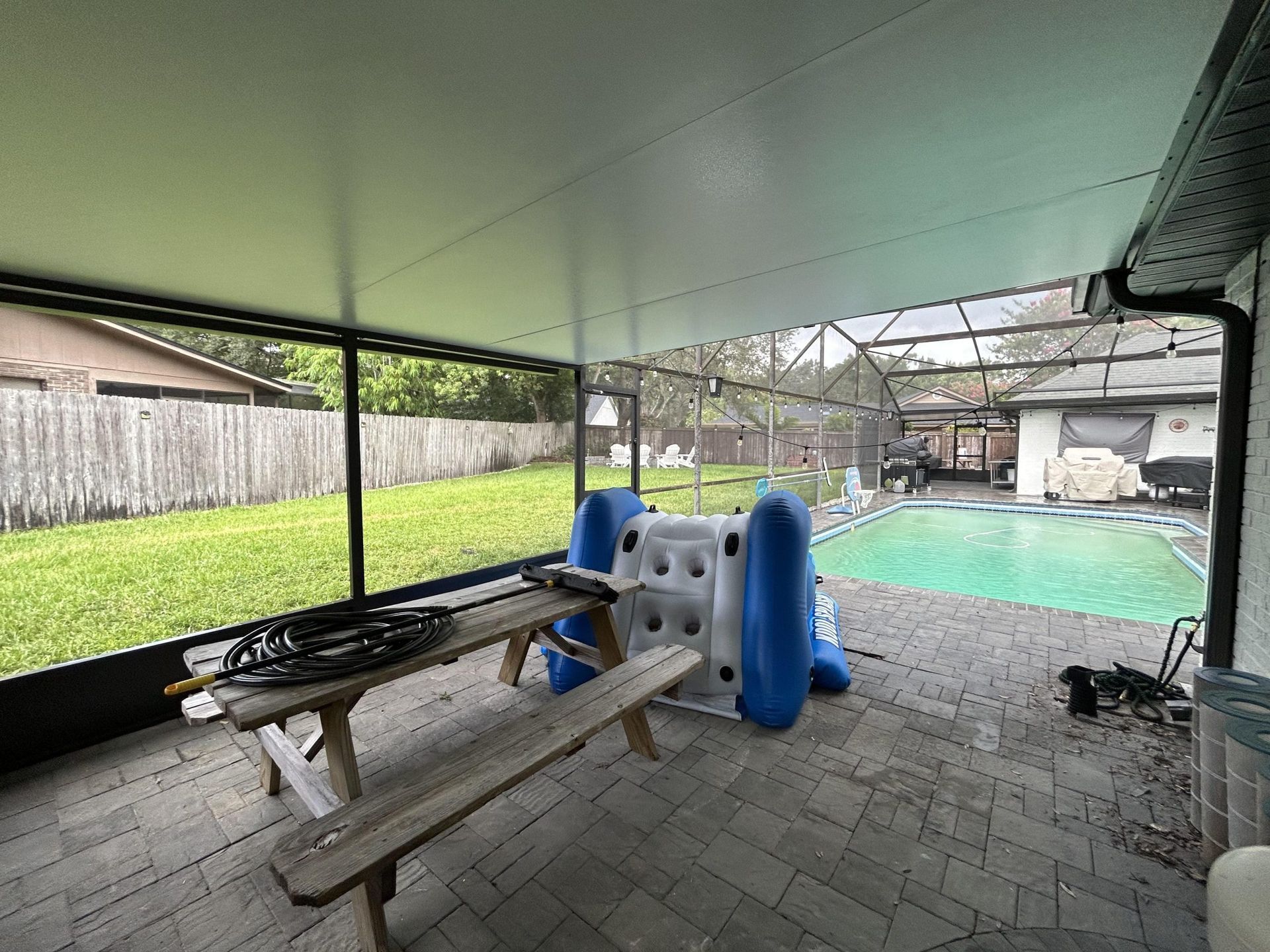 A screened in porch with a picnic table and a pool
