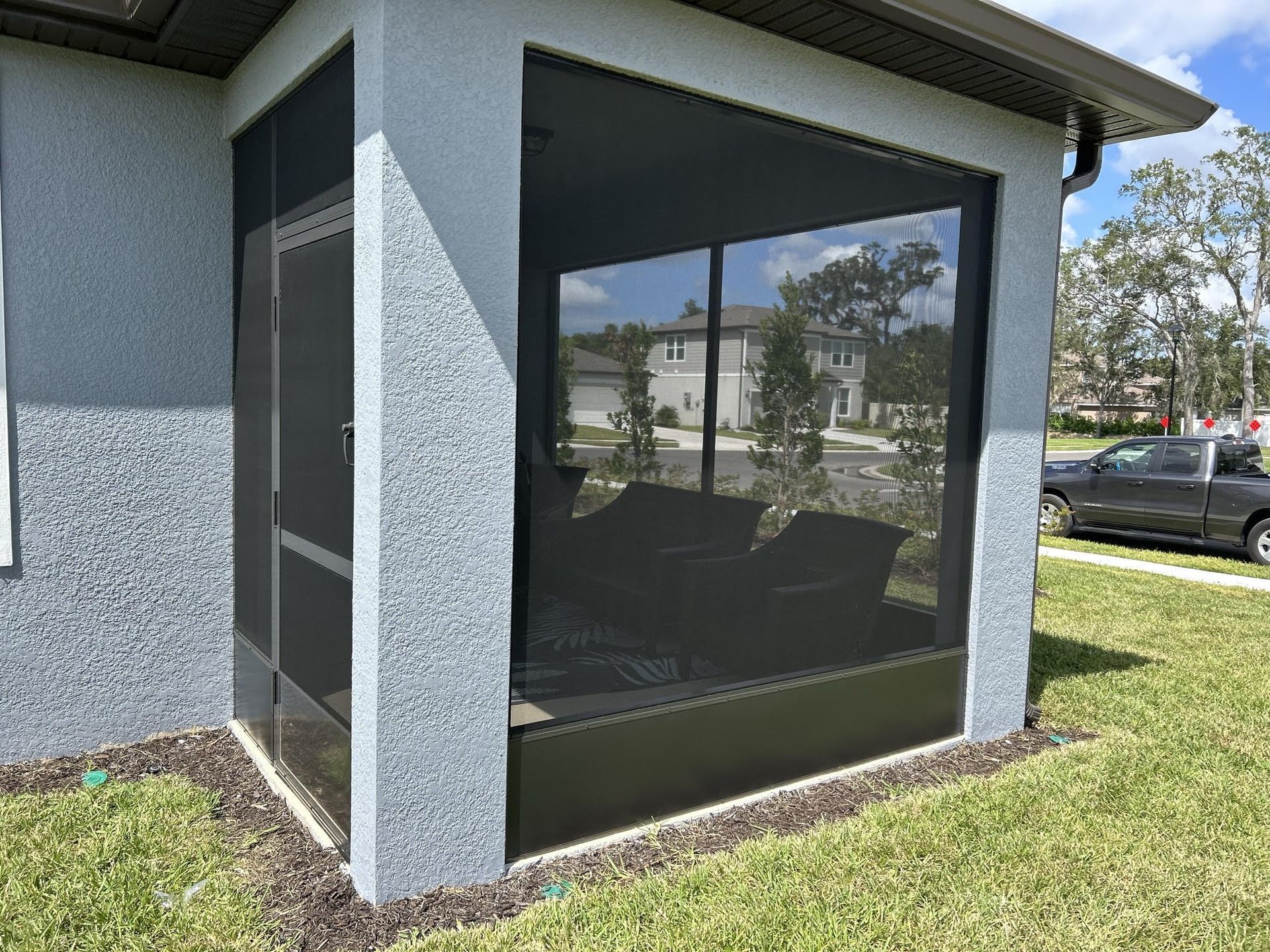 A house with a screened in porch and a truck parked in front of it