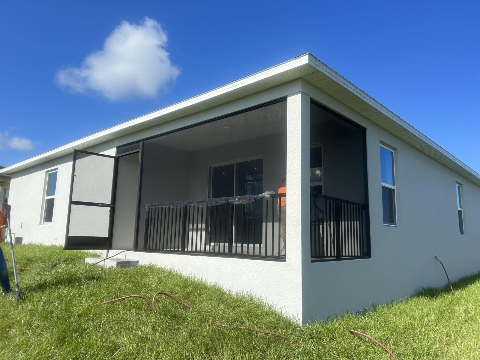 A white house with a screened in porch and a black railing