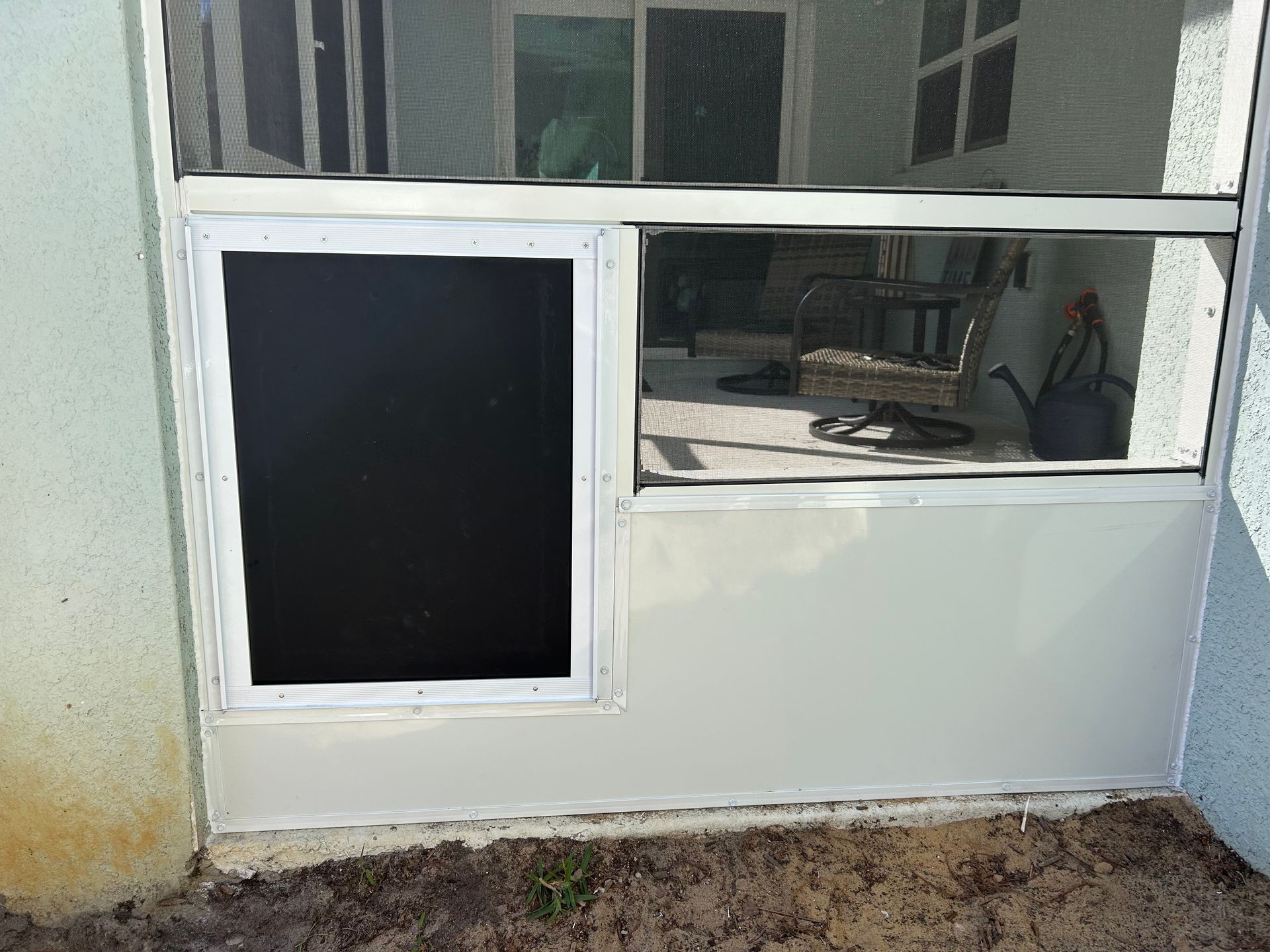 A screened in window with a black screen on the side of a house