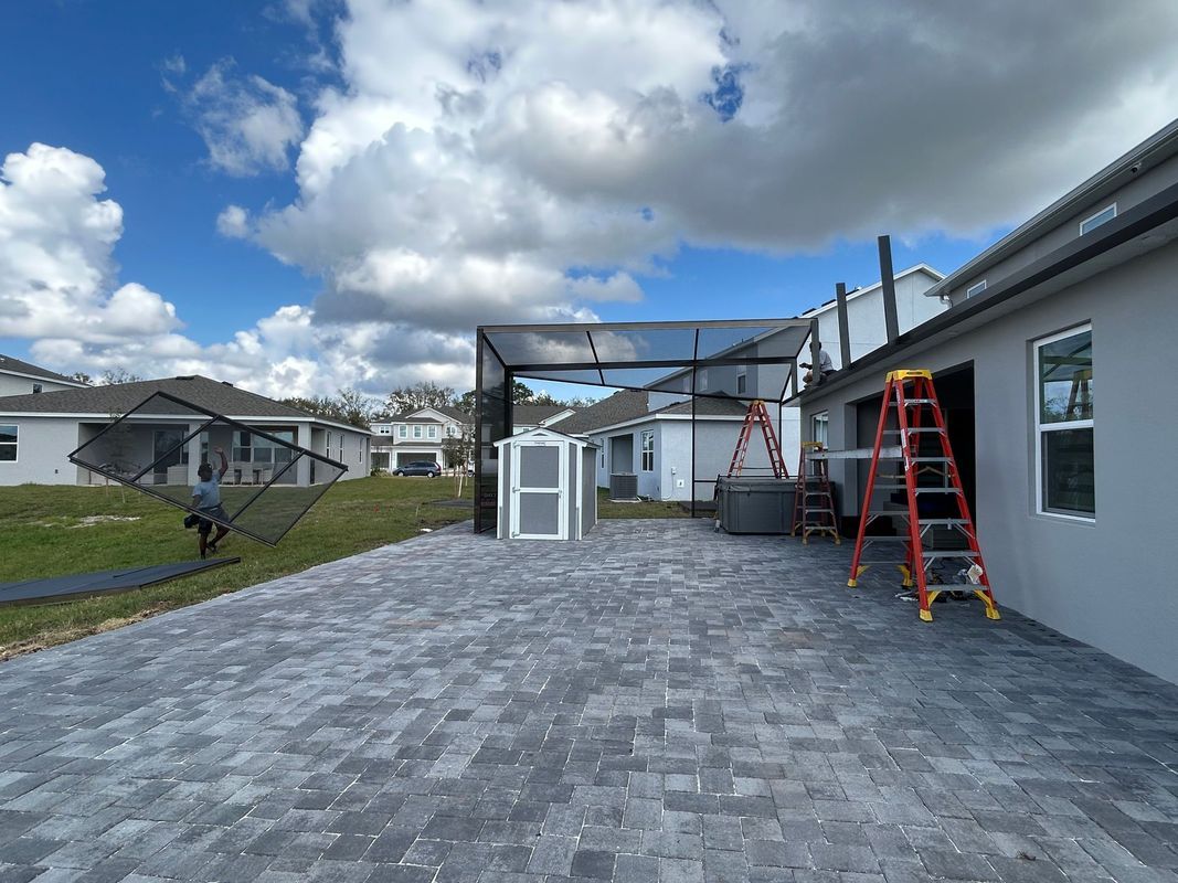 A brick driveway leading to a house with a ladder in front of it