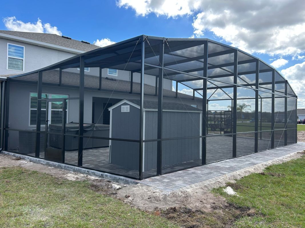 A screened in porch with a shed and a hot tub in the backyard of a house