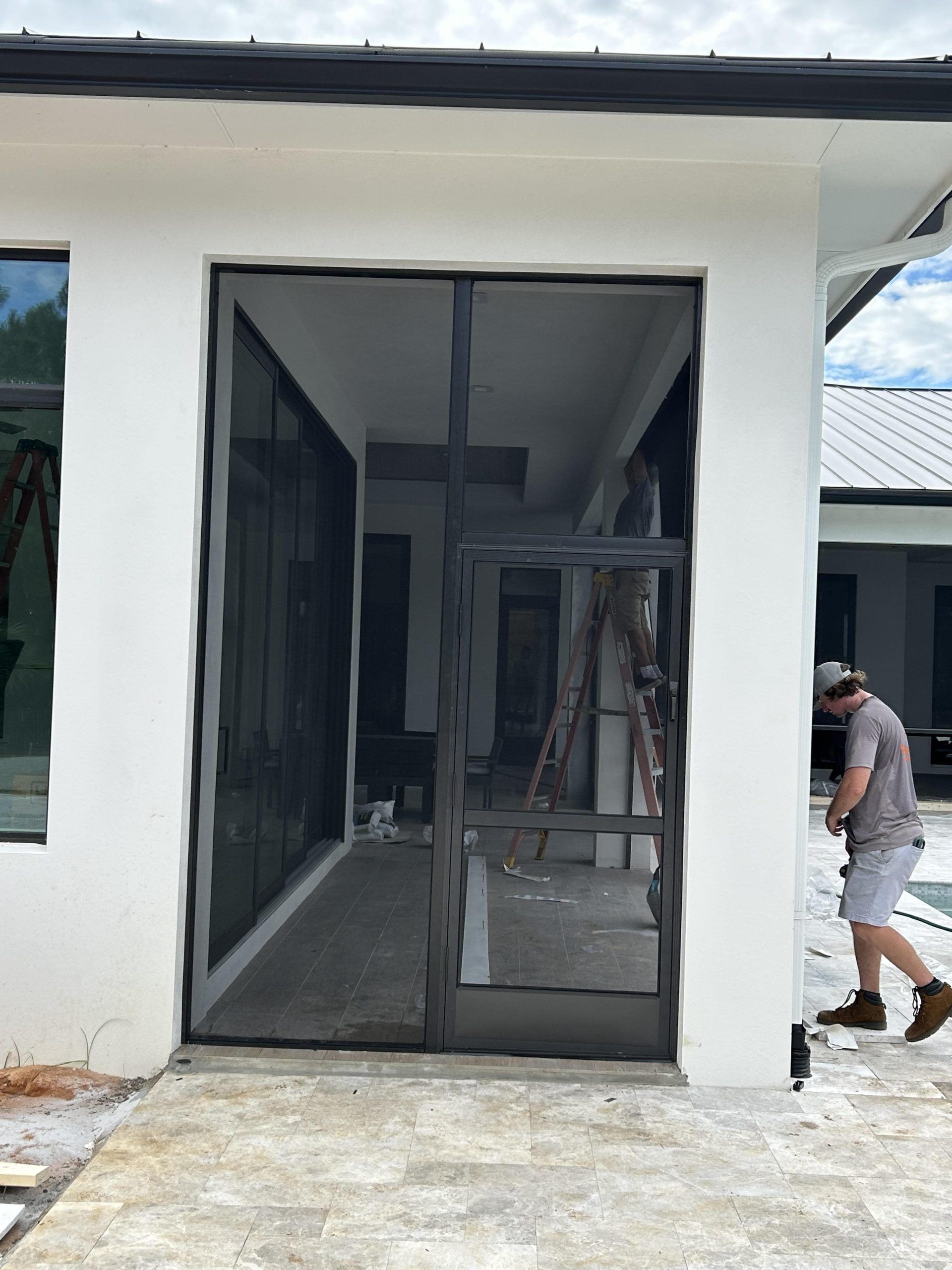 A man is standing in front of a screen door in a house