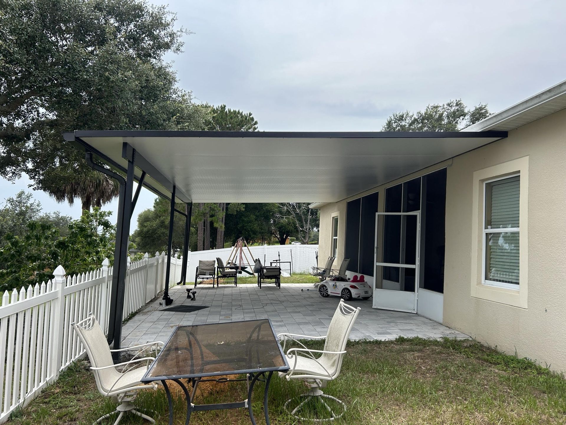 A patio with a table and chairs under a carport