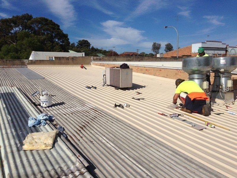 A Man is Measuring a Roof With a Tape Measure — Coast Metal Roof & Gutter In Tumbi Umbi, NSW