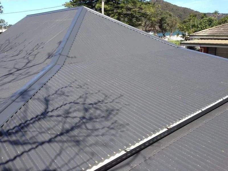 A Black Roof With a Tree Shadow on It — Coast Metal Roof & Gutter In Tumbi Umbi, NSW