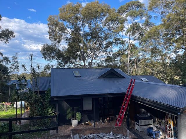Two Men Are Working on the Roof of a Building — Coast Metal Roof & Gutter In Lake Macquarie, NSW