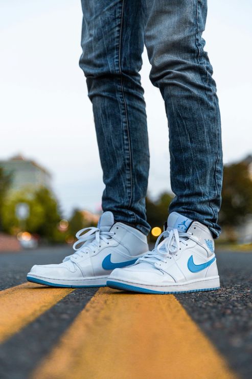 Una persona lleva un par de zapatillas Nike blancas y azules.