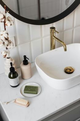 A bathroom with a sink , mirror and soap on the counter.