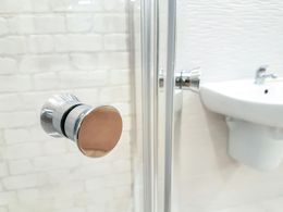 A close up of a shower door in a bathroom with a sink.