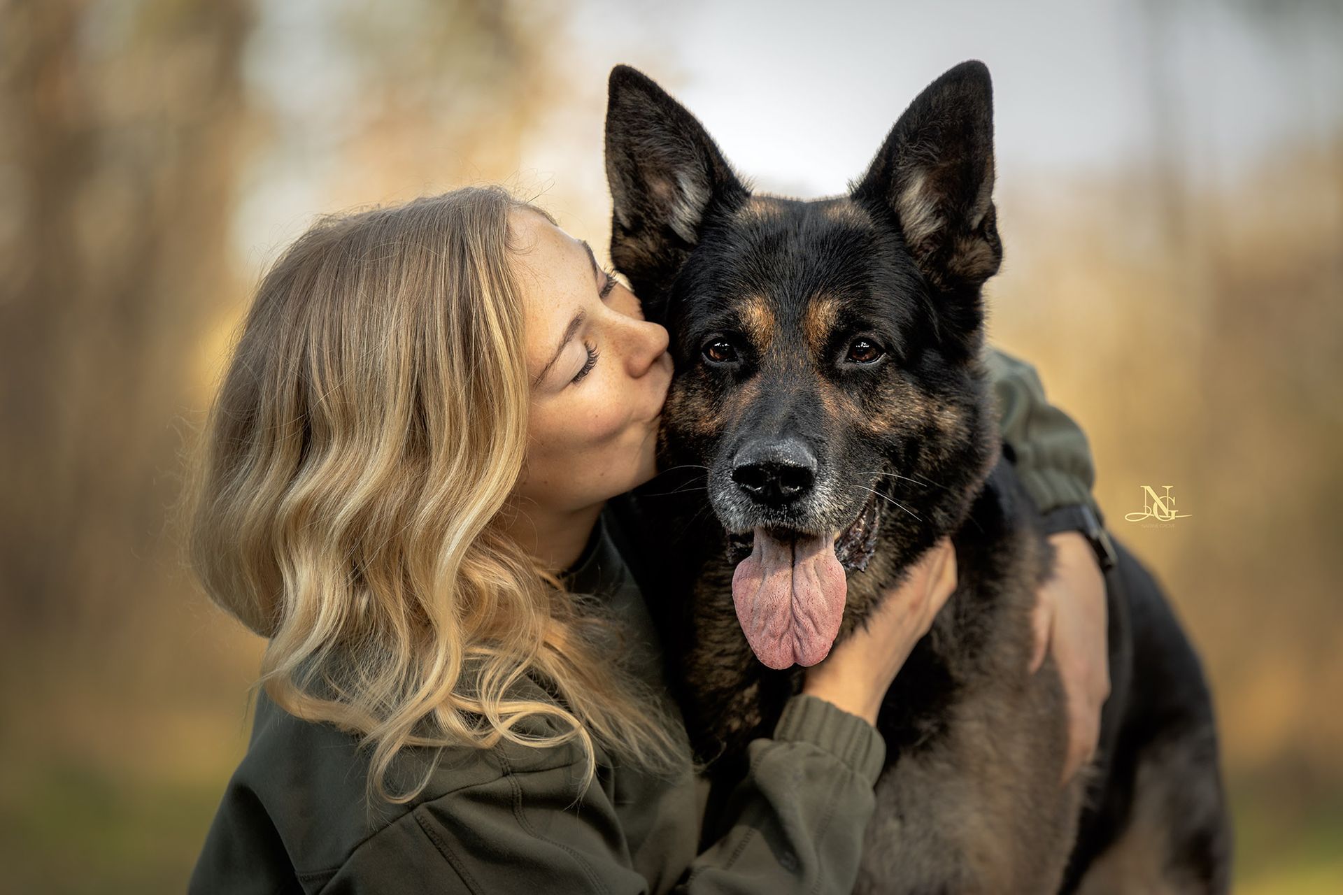 Portrait einer Frau und ihres Schäferhundes. Der Hund wird liebevoll umarmt und geküsst.