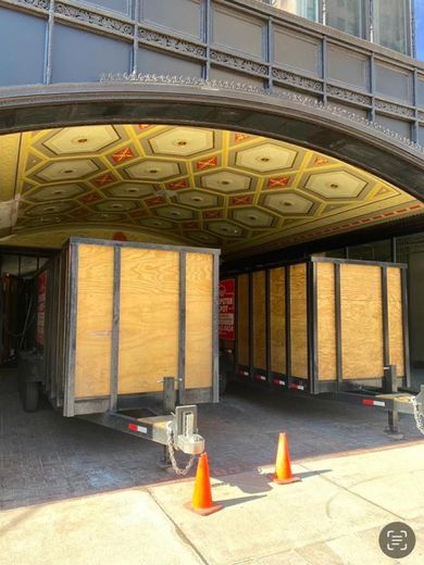 Two trailers under a decorative archway. Orange cones in front.