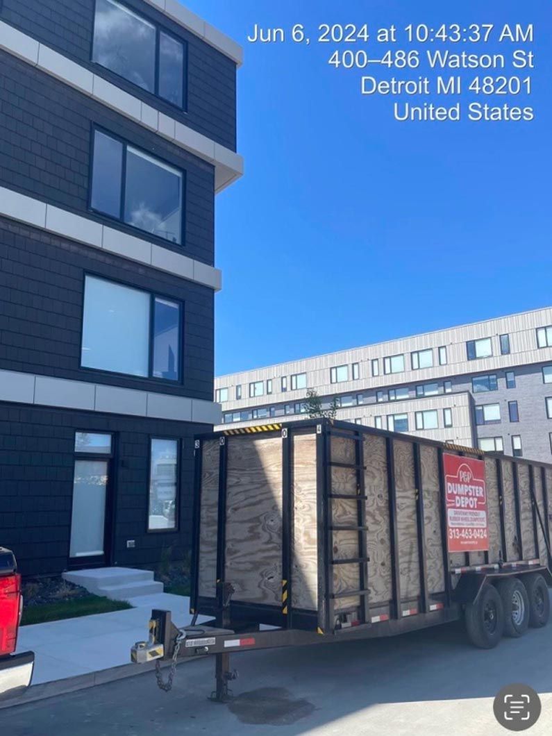A trailer loaded with materials in Detroit, MI, near a modern building on a sunny day.