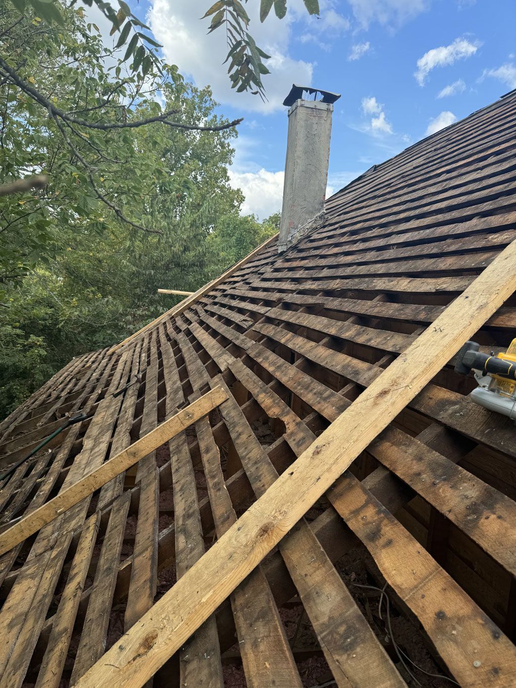 A roof with wooden beams and a chimney in the background.