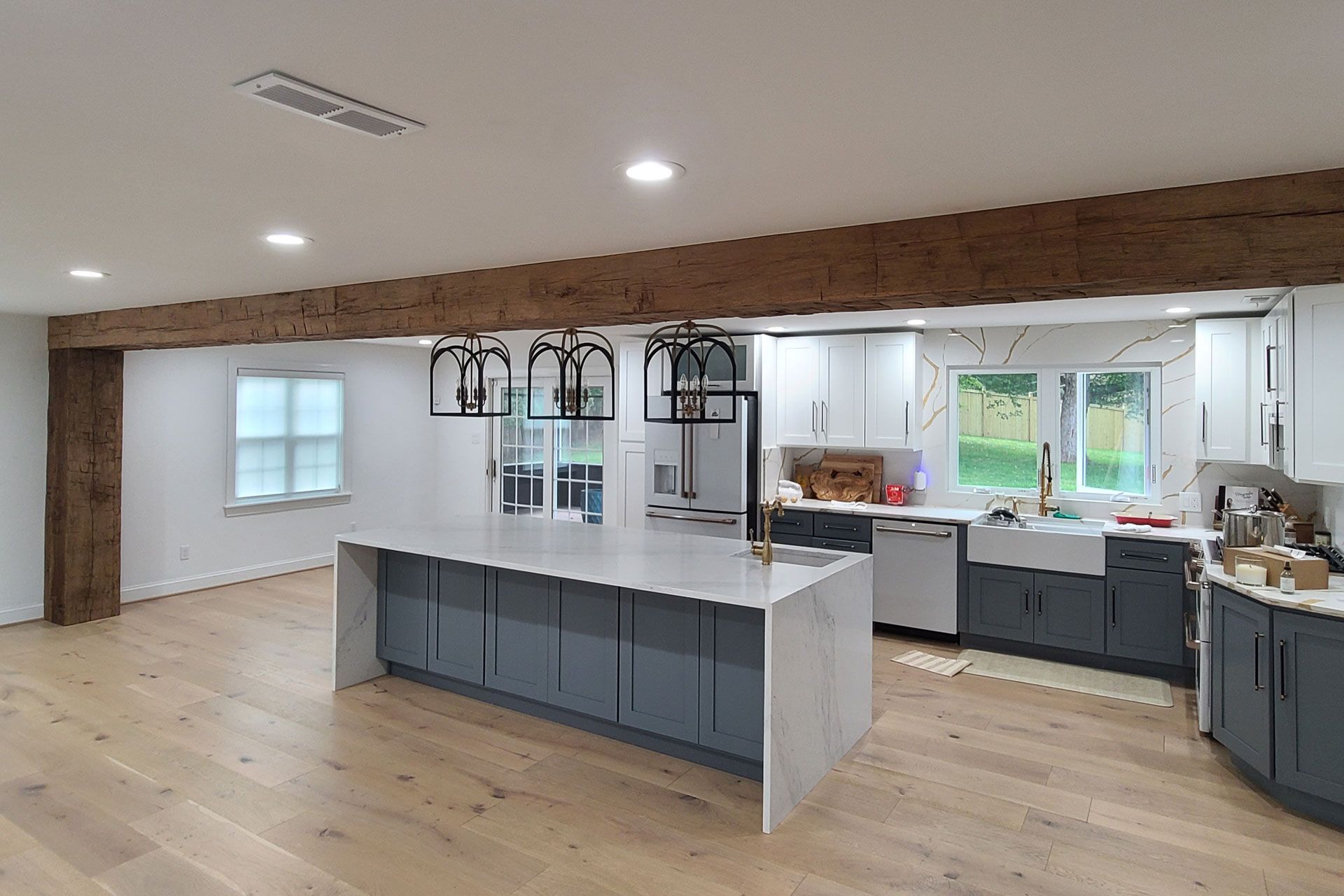 Open-concept kitchen with island, gray cabinets, light wood floor, and exposed beam.| Rebuck, PA | Expressions Carpentry