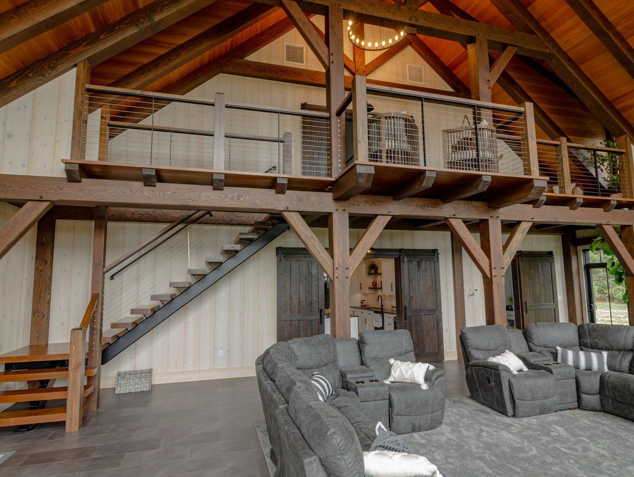 A large red barn with a lot of windows is sitting on top of a lush green field.