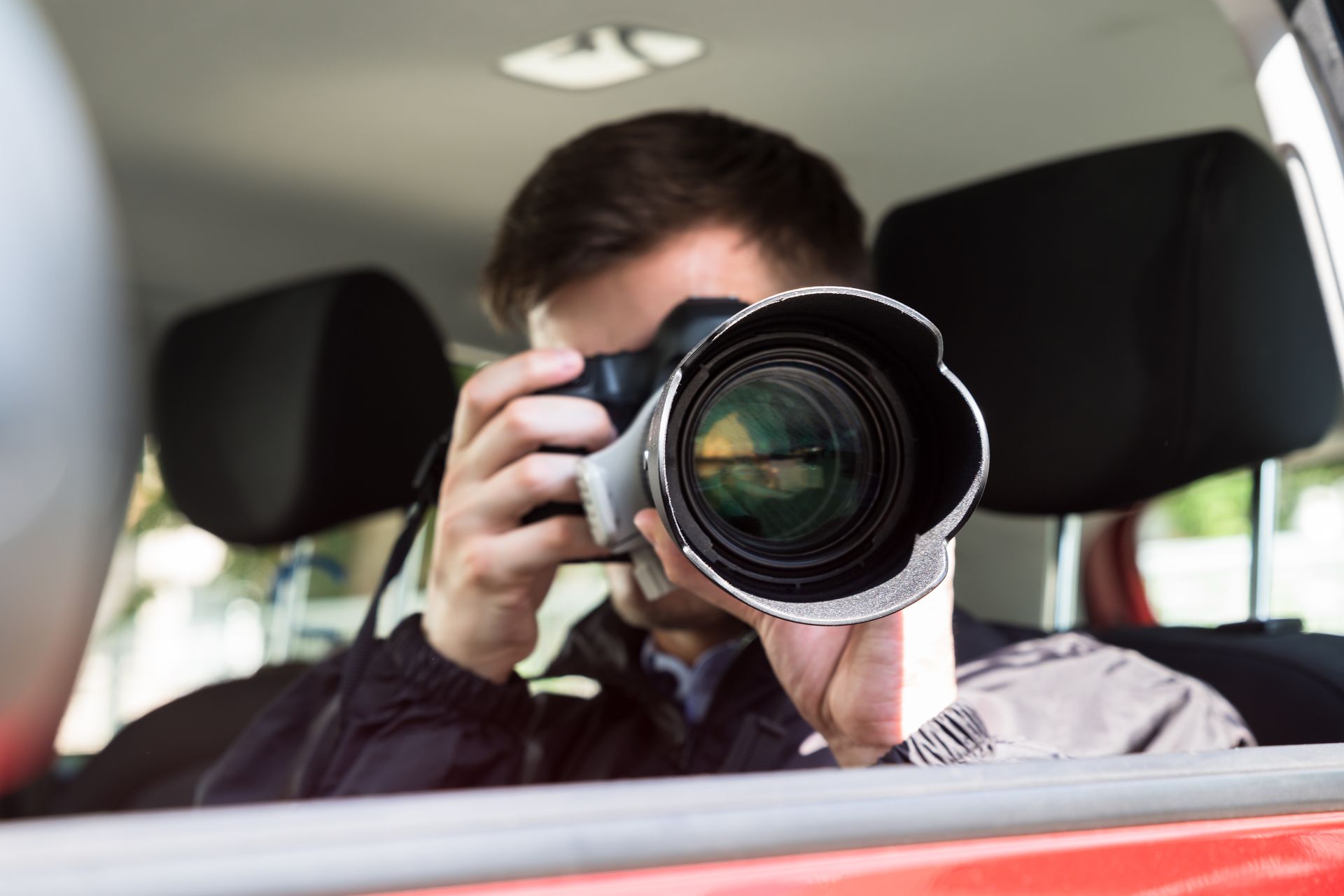 Side View Of A Private Detective Sitting Inside Car Photographing With Slr Camera