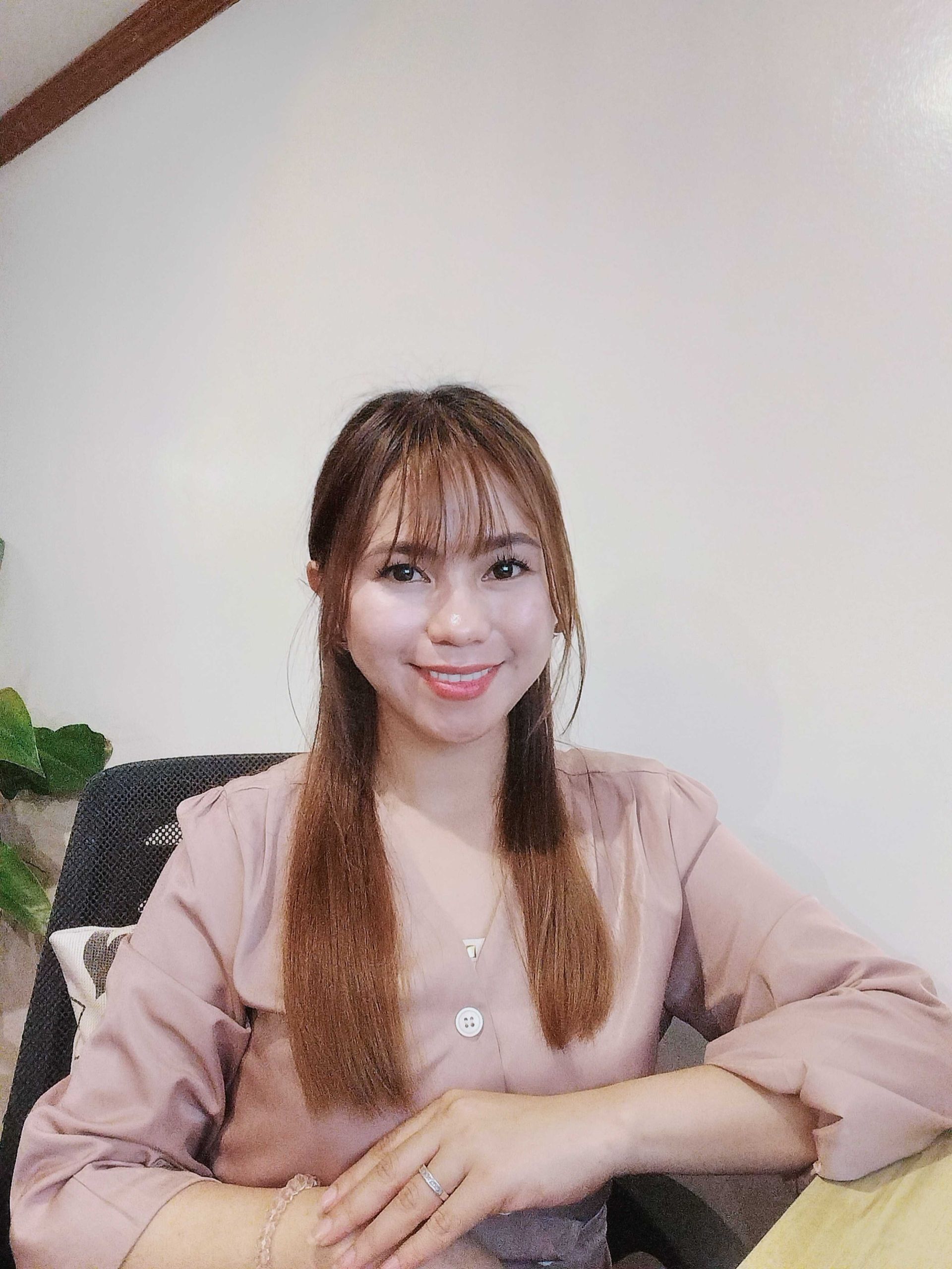 Woman wearing a white shirt and a jeweled headband, smiling with red lipstick.