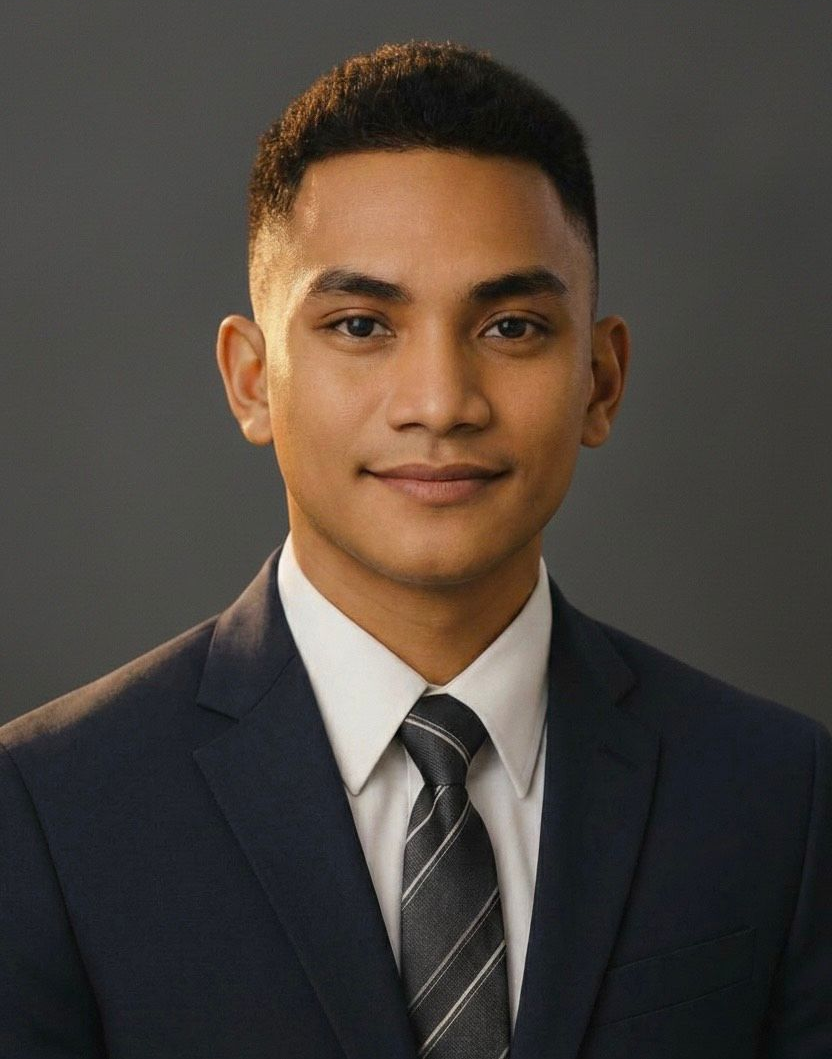 Woman with curly brown hair, wearing a white shirt and black blazer, smiling at the camera.