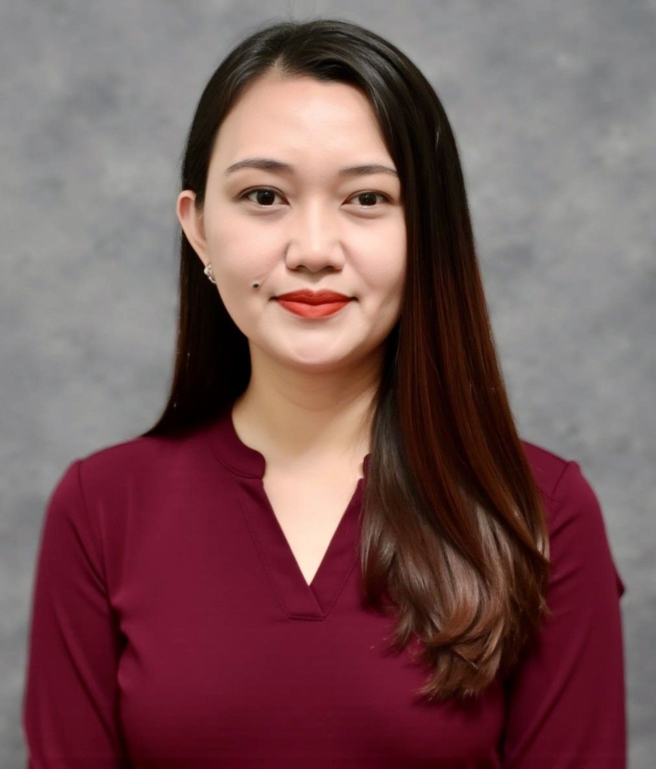 Woman wearing a white shirt and a jeweled headband, smiling with red lipstick.