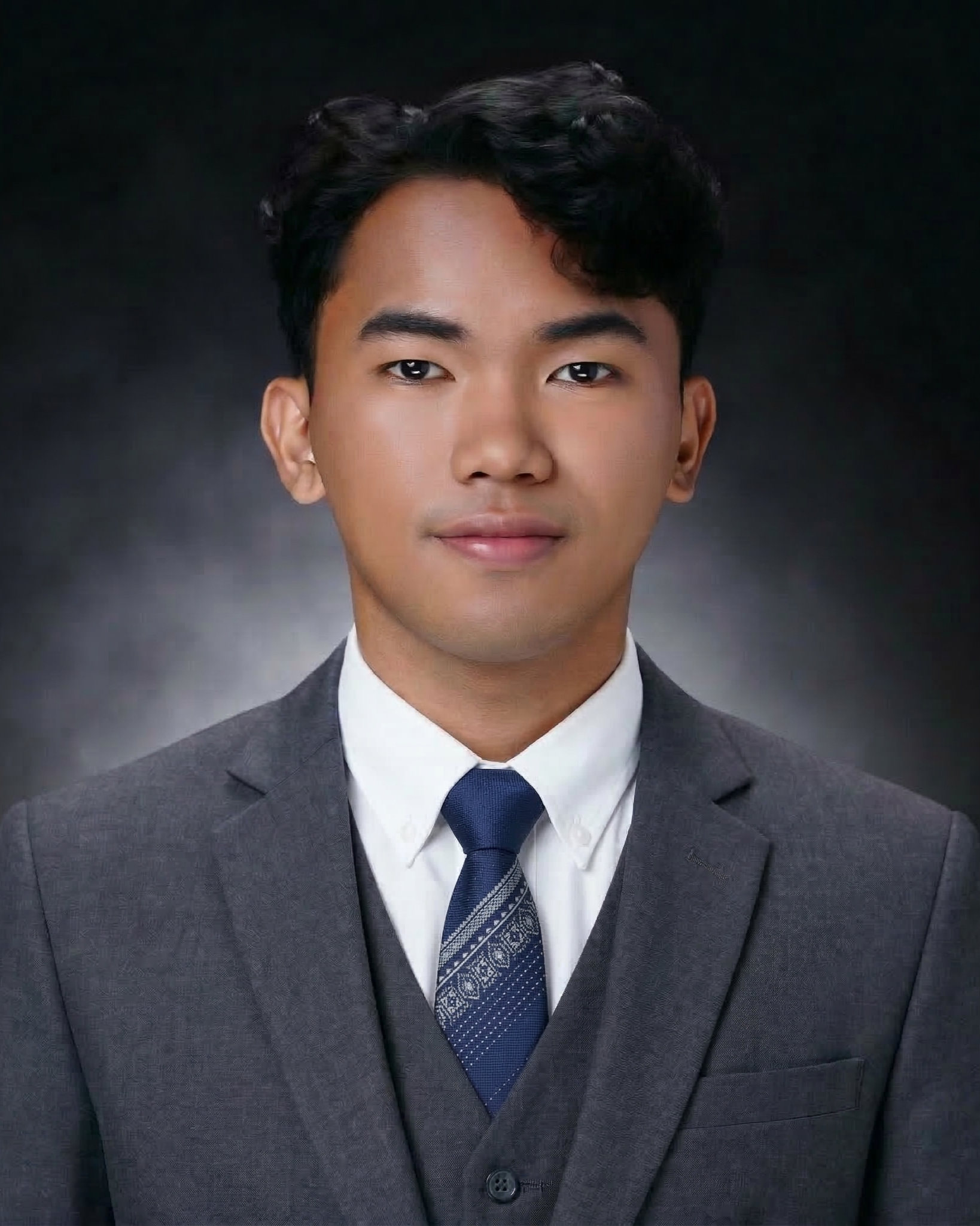 Woman with curly brown hair, wearing a white shirt and black blazer, smiling at the camera.
