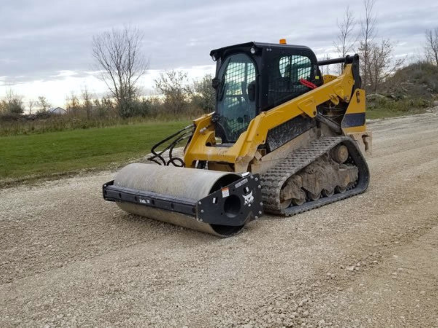 A track loader compacts a freshly graded gravel driveway in Davenport, Illinois.