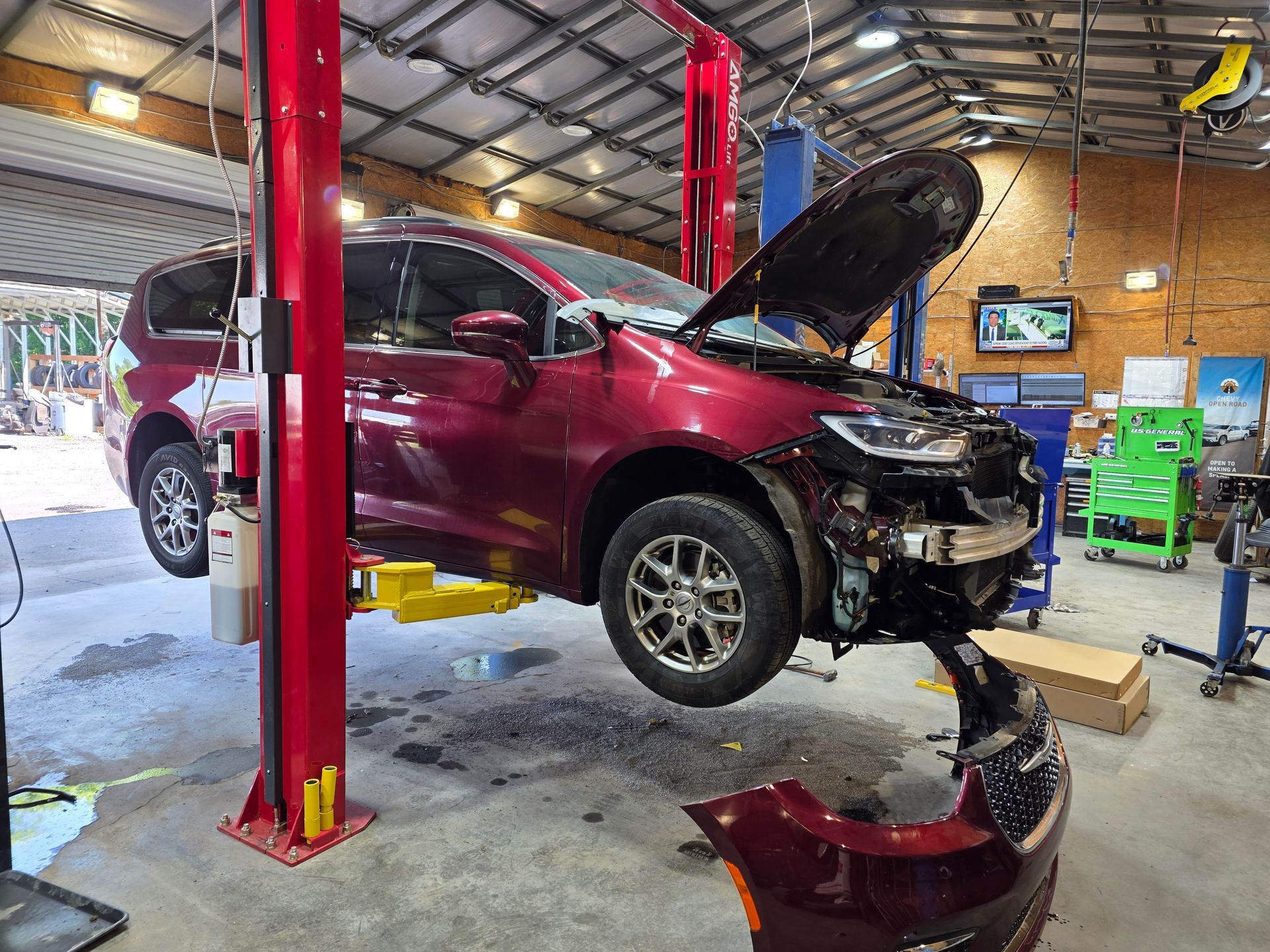 Maroon SUV on a lift in an auto shop with its hood open and front bumper removed | Masters Auto Group