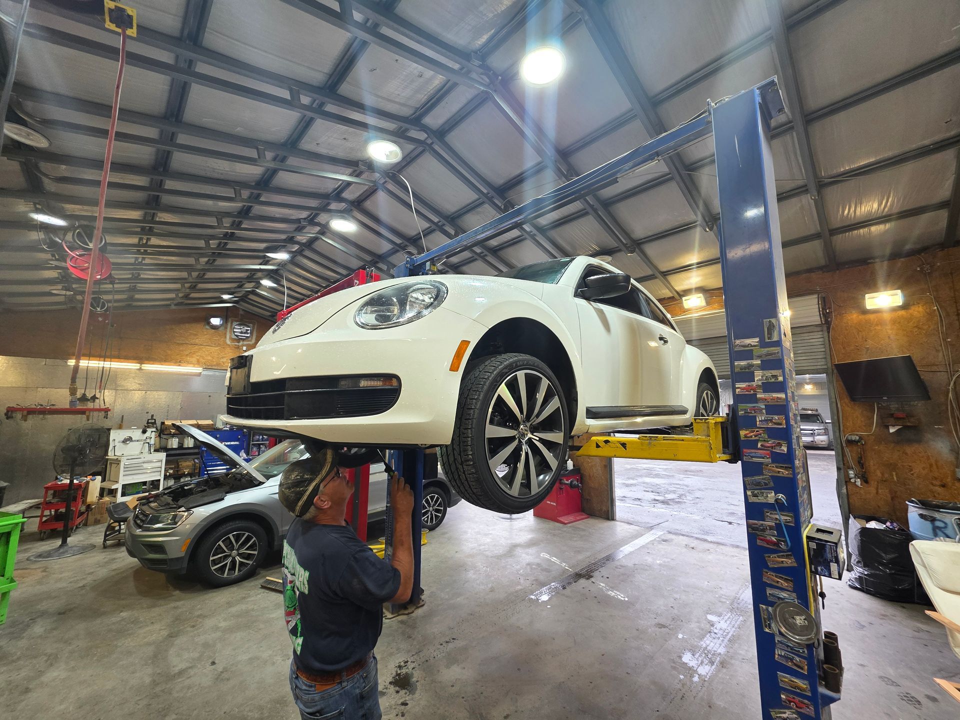 White car lifted on a garage hoist while a mechanic works underneath in an auto shop | Masters Auto Group
