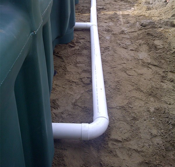 Un tuyau blanc repose dans la terre à côté d'un réservoir vert