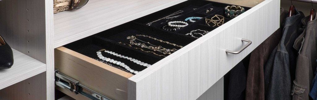 A drawer filled with necklaces and bracelets in a closet.