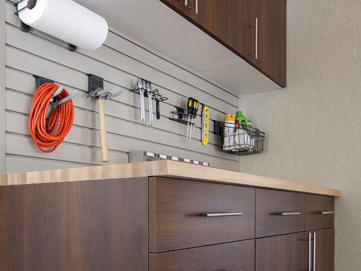 a workbench with wooden cabinets , a paper towel holder , and a hose hanging on the wall .