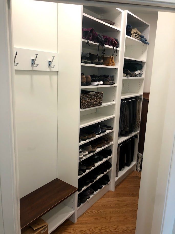a walk in closet with lots of shelves and a bench .