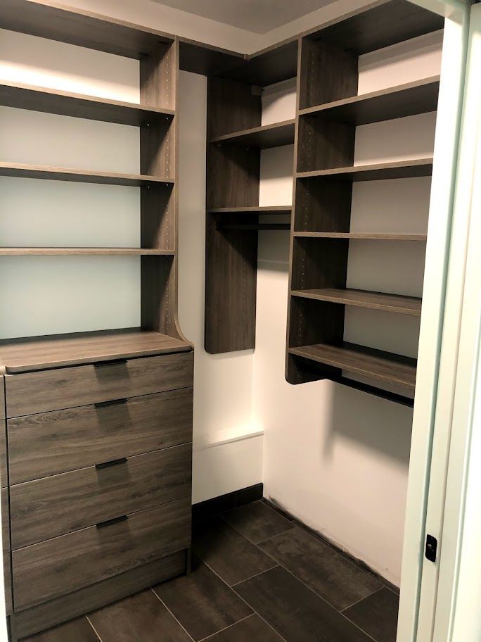 a walk in closet with lots of shelves and drawers
